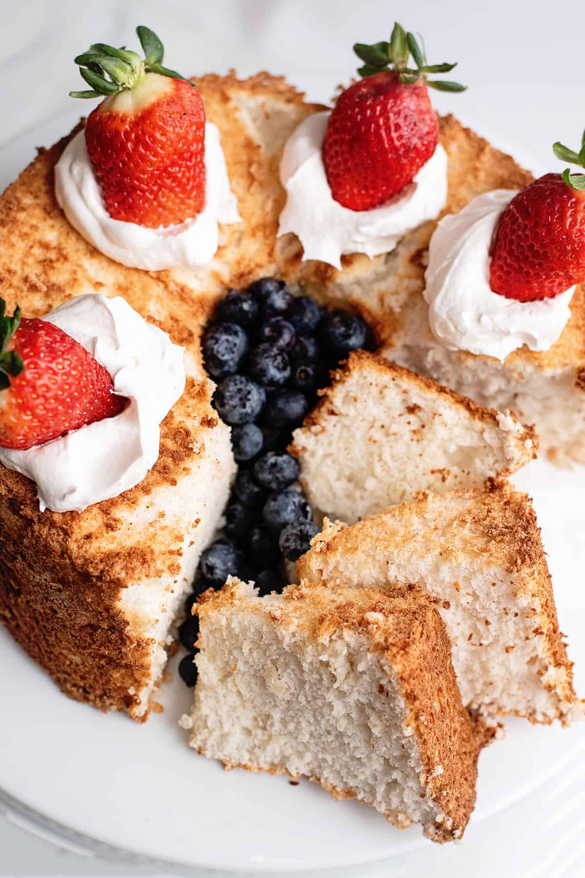 angel food cake sliced and topped with cream and berries