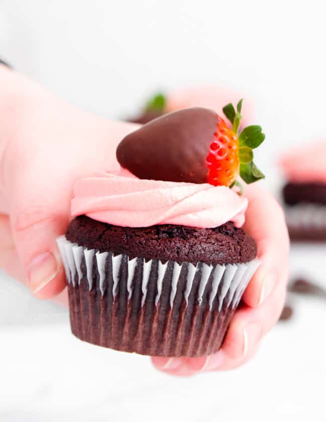 hand holding up chocolate covered strawberry cupcake