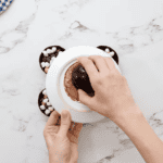 melting the edges of a chocolate half-sphere on a white plate.