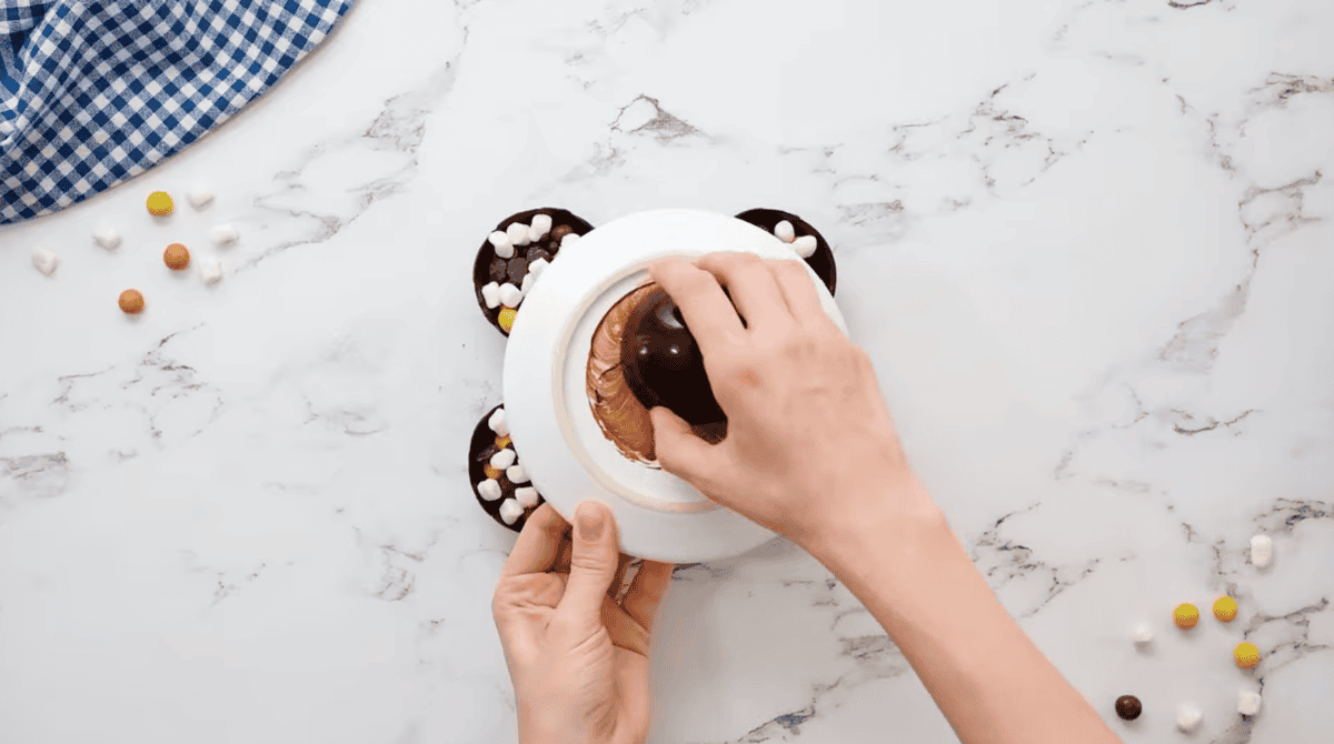 melting the edges of a chocolate half-sphere on a white plate.