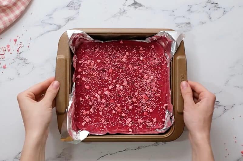 red velvet fudge topped with valentine's day sprinkles in a foil-lined baking pan.