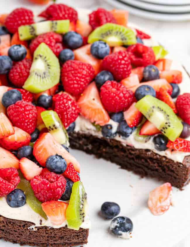 brownie fruit pizza topped with cream and sliced fruit