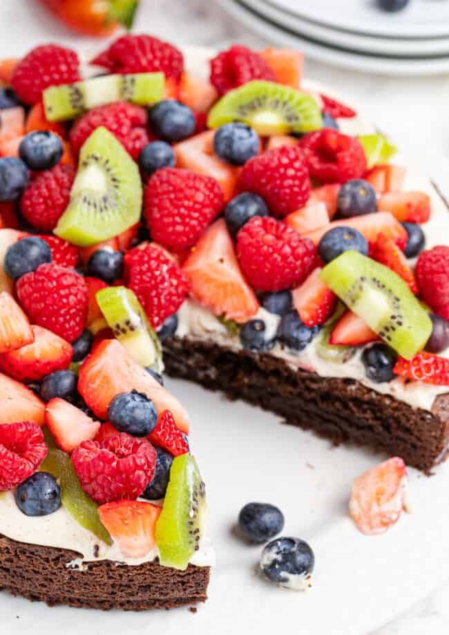 brownie fruit pizza topped with cream and sliced fruit