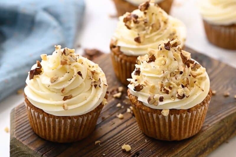 frosted carrot cake cupcakes topped with chopped nuts.