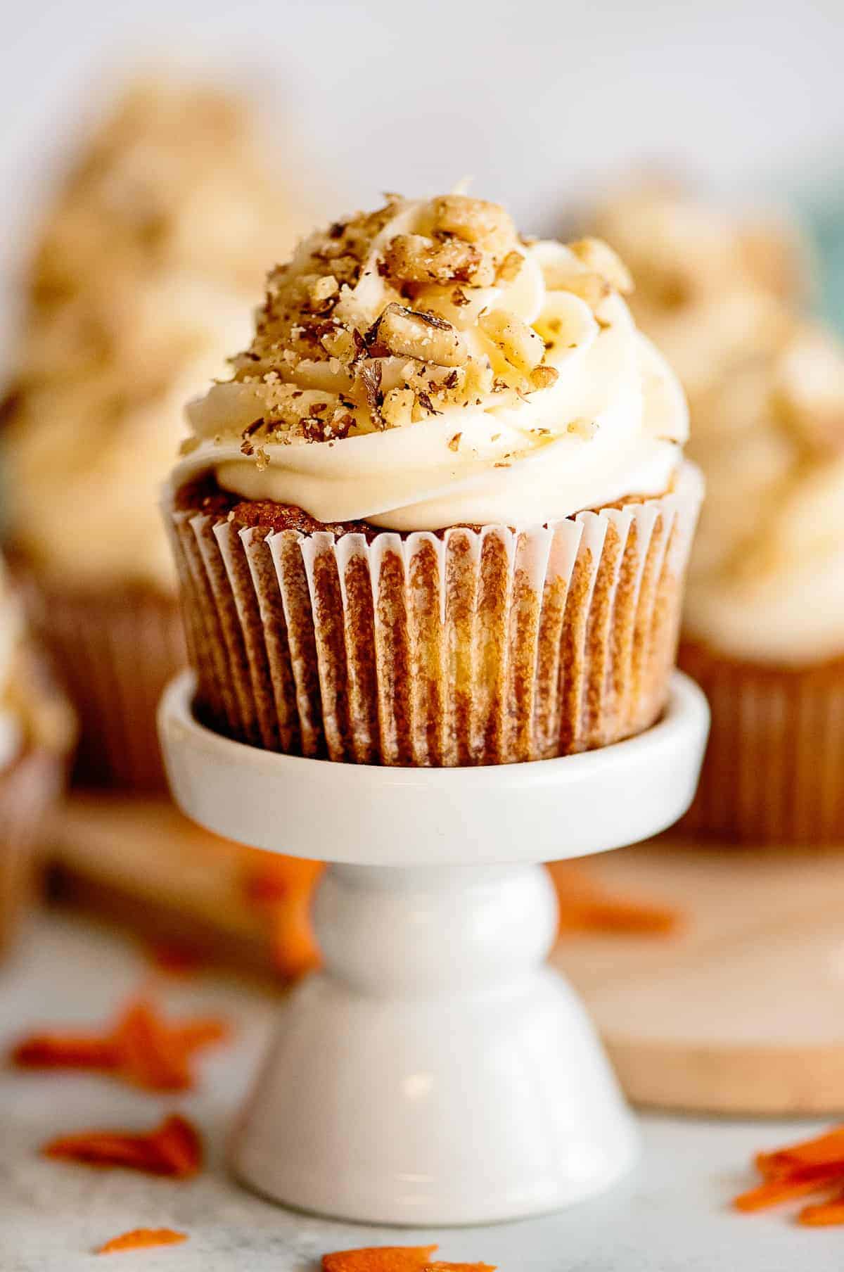 carrot cake cupcake garnished with nuts on cupcake stand