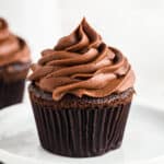 chocolate cupcake with chocolate buttercream frosting on white plate