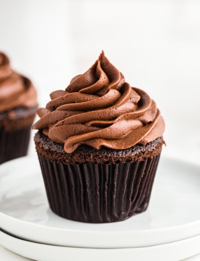 chocolate cupcake with chocolate buttercream frosting on white plate