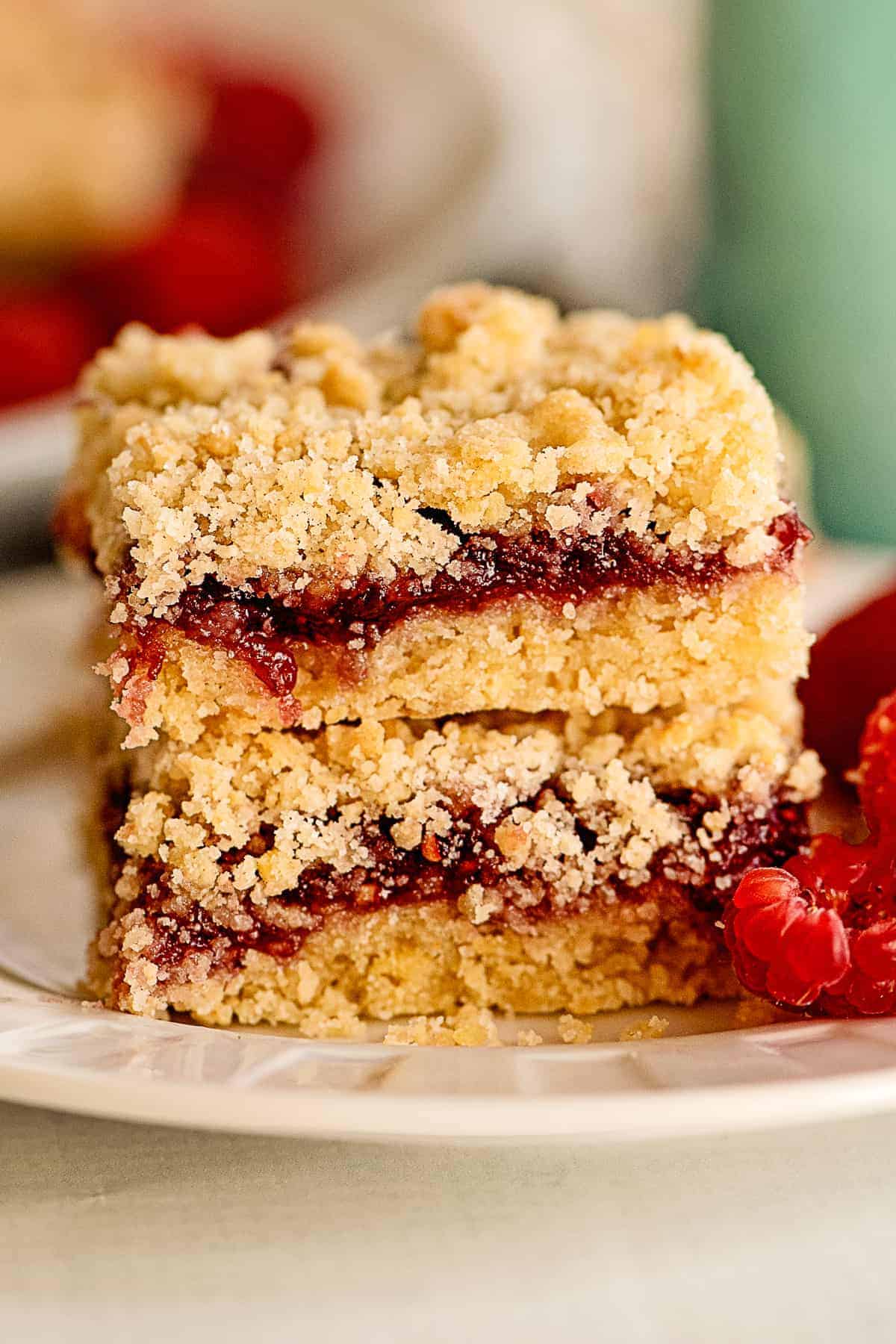 up close stacked raspberry crumb bars on white plate