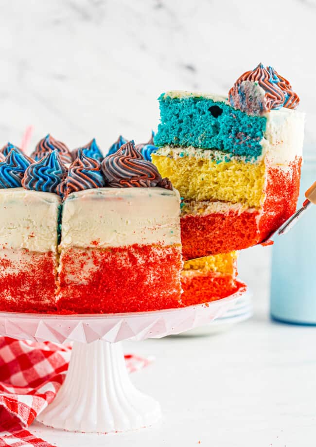 lifting up slice of 4th of july layer cake with red white and blue layers