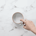 spraying nonstick spray into a ceramic mug.