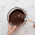 melted chocolate in a glass bowl with a rubber spatula.