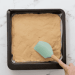 spreading peanut butter mixture into a baking pan wit a rubber spatula.