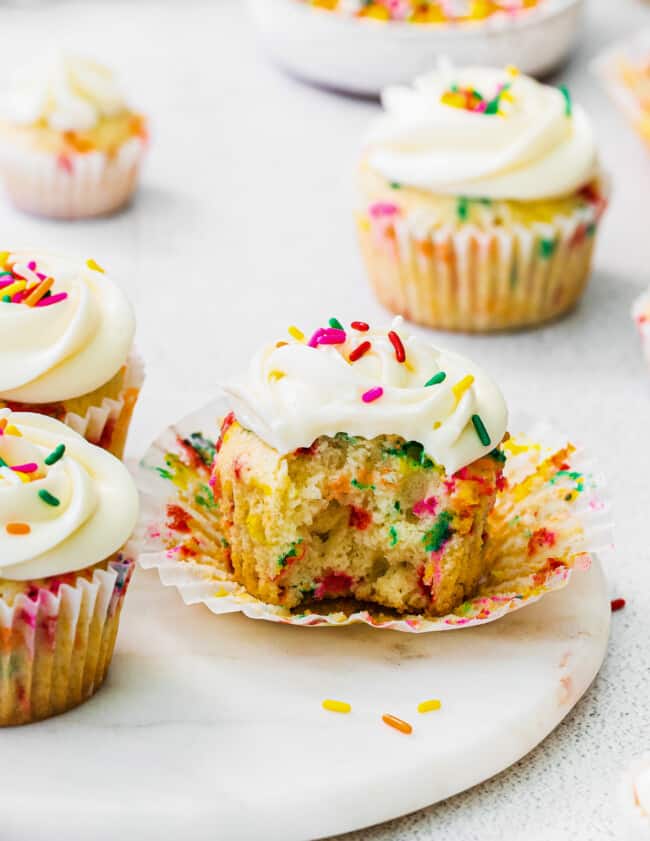 bite out of funfetti cupcake with frosting and sprinkles