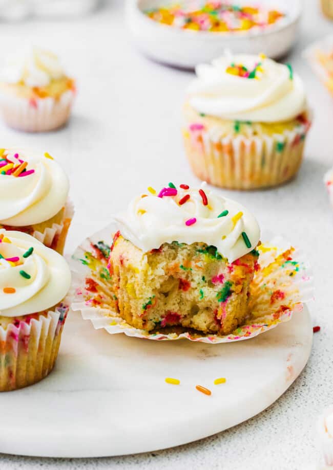 bite out of funfetti cupcake with frosting and sprinkles
