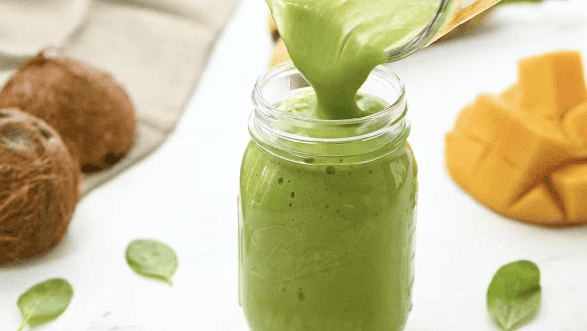 pouring an island green smoothie into a mason jar.