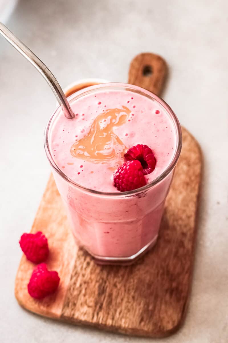 peanut butter and jelly smoothies garnished with raspberries and peanut butter