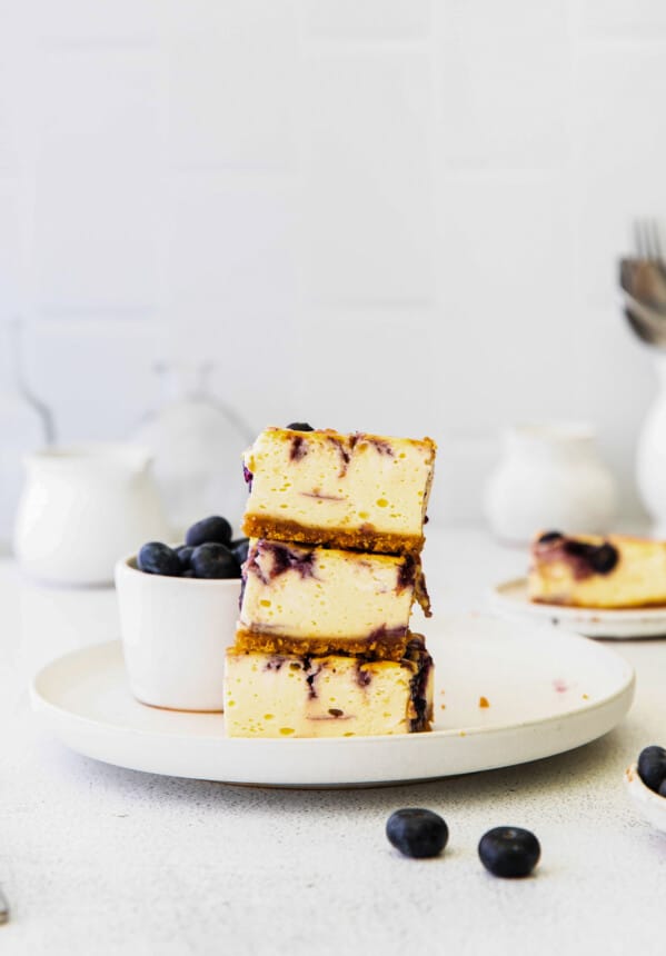 stack of 3 blueberry cheesecake bars on a white plate
