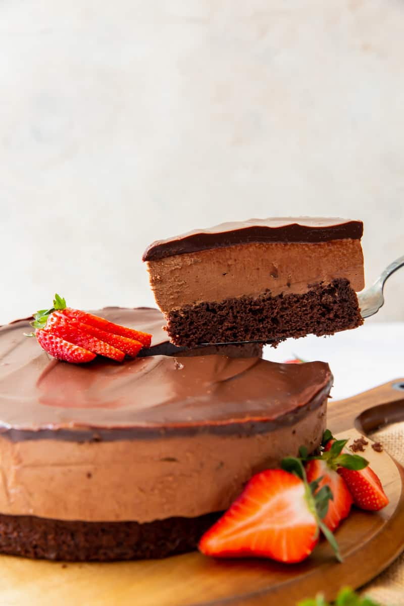 slice of chocolate mousse cake being removed from the full cake on a cake server
