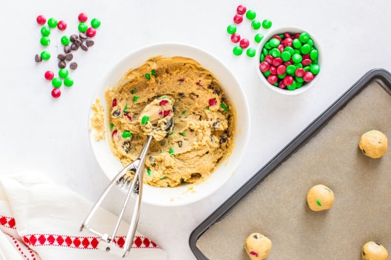 christmas M&M cookie dough in a bowl with a cookie scoop