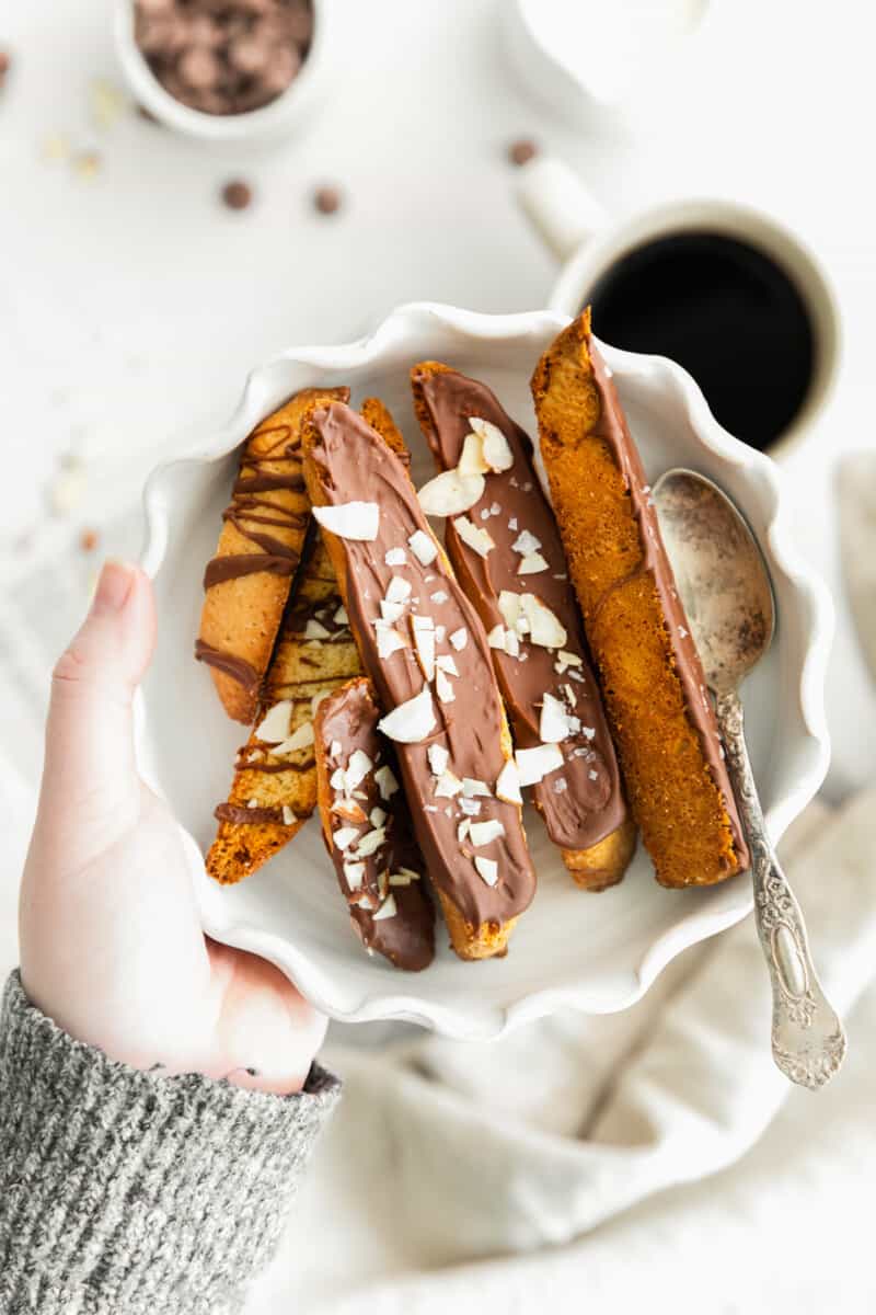 hand holding bowl of chocolate dipped biscotti