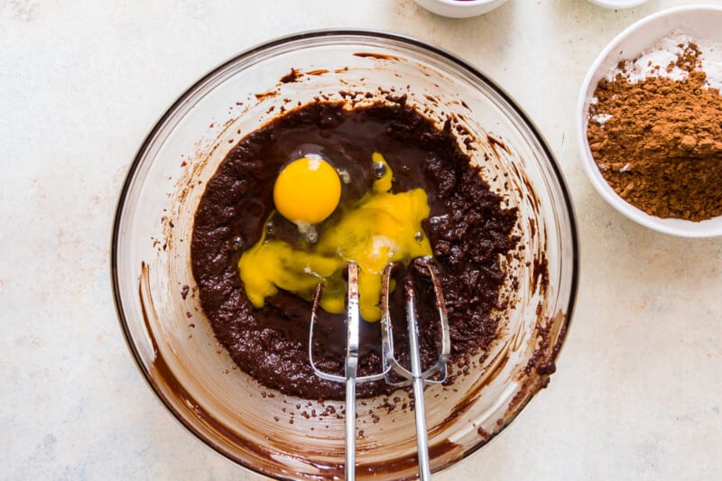 eggs added to brownie batter in a glass bowl