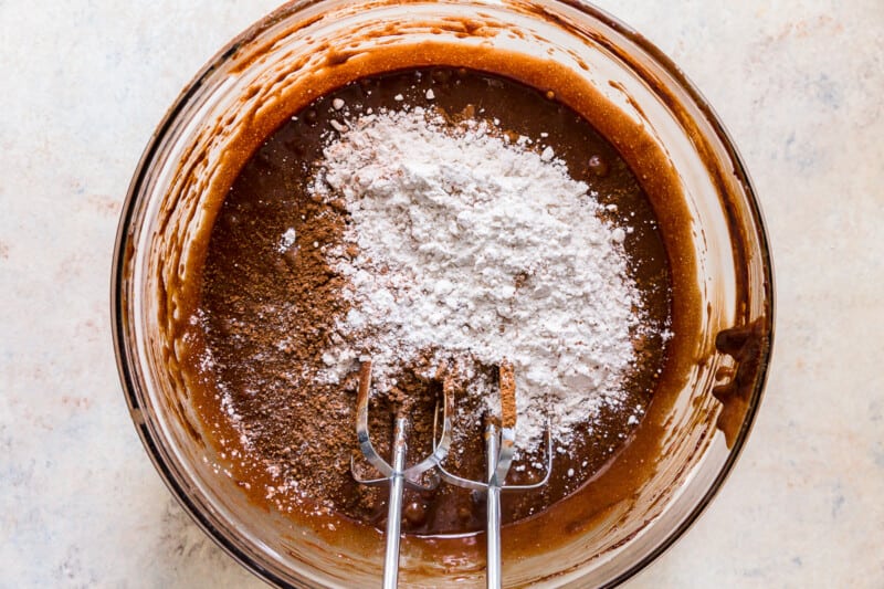 dry ingredients added to brownie batter in a glass bowl
