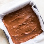 brownie batter in a parchment paper lined square pan before baking