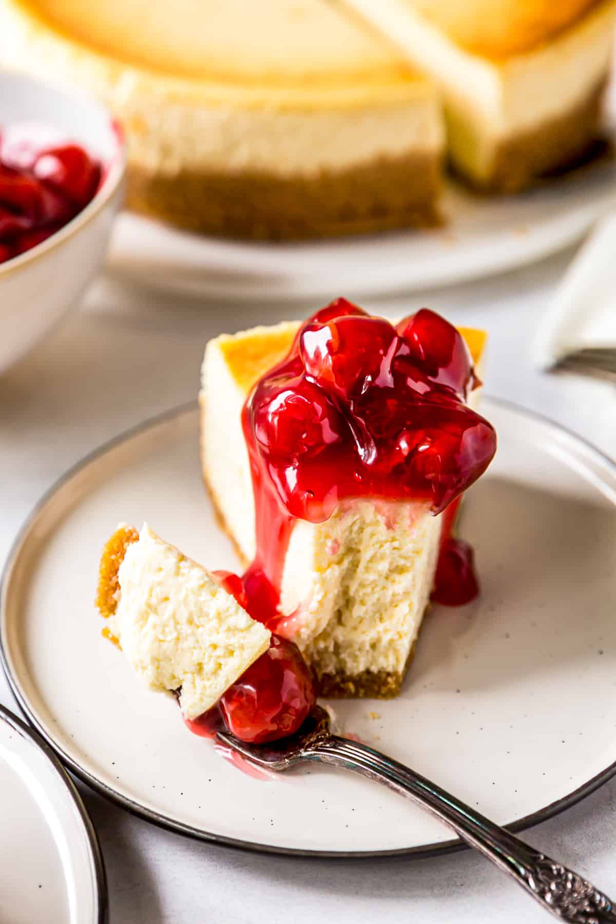 new york cheesecake topped with cherries with bite out