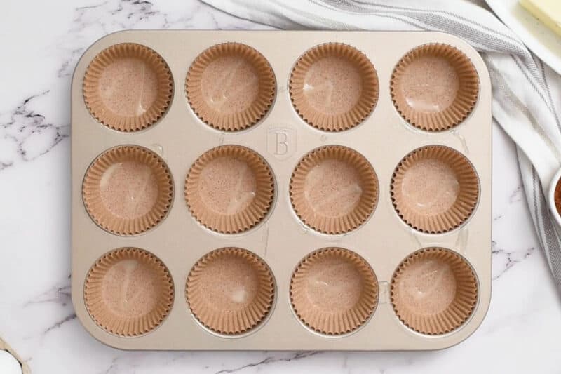 cupcake liners sprayed with nonstick spray in a cupcake tin.