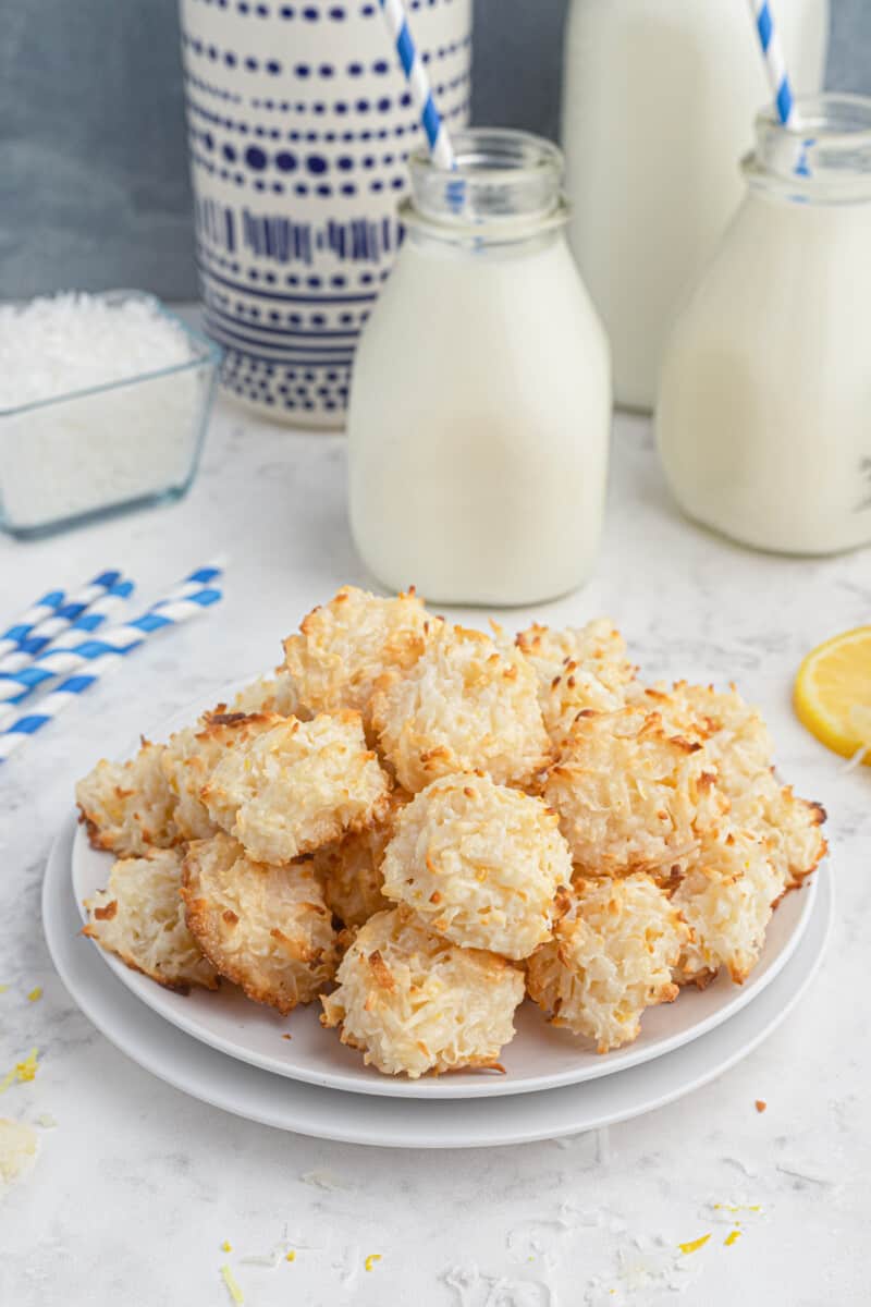 coconut macaroons on a white plate with jugs of milk.