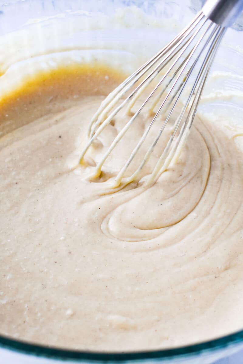 eggnog sheet cake batter in a glass bowl with a whisk.