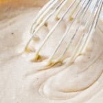 eggnog sheet cake batter in a glass bowl with a whisk.