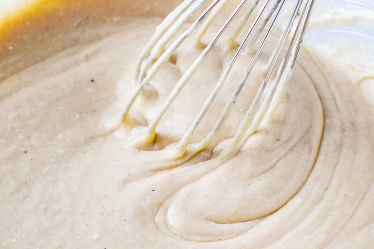 eggnog sheet cake batter in a glass bowl with a whisk.