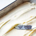 frosted eggnog sheet cake in a 9x13 pan with an offset spatula.