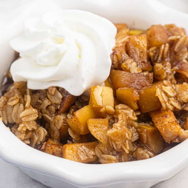 up close bowl of instant pot apple crisp with whipped cream