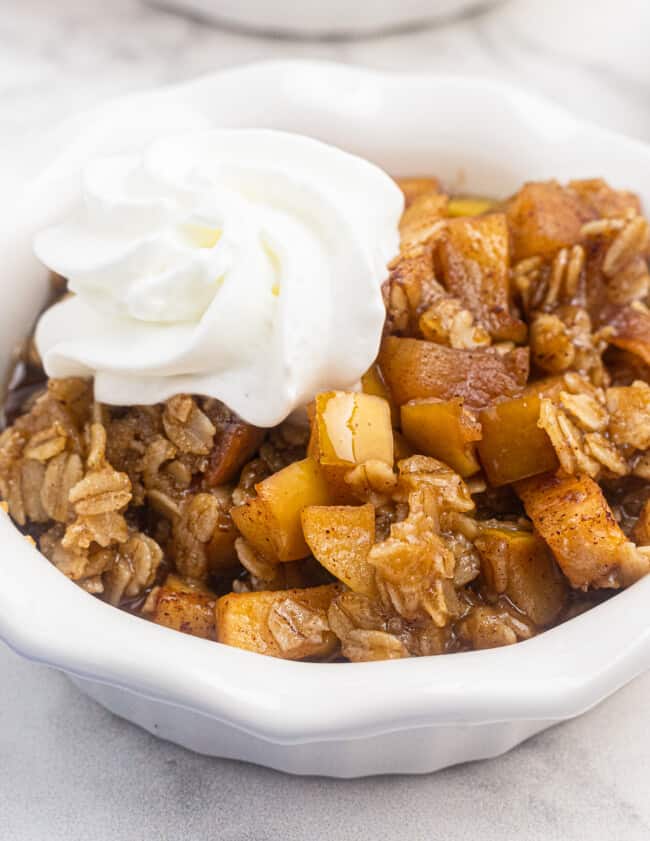 up close bowl of instant pot apple crisp with whipped cream