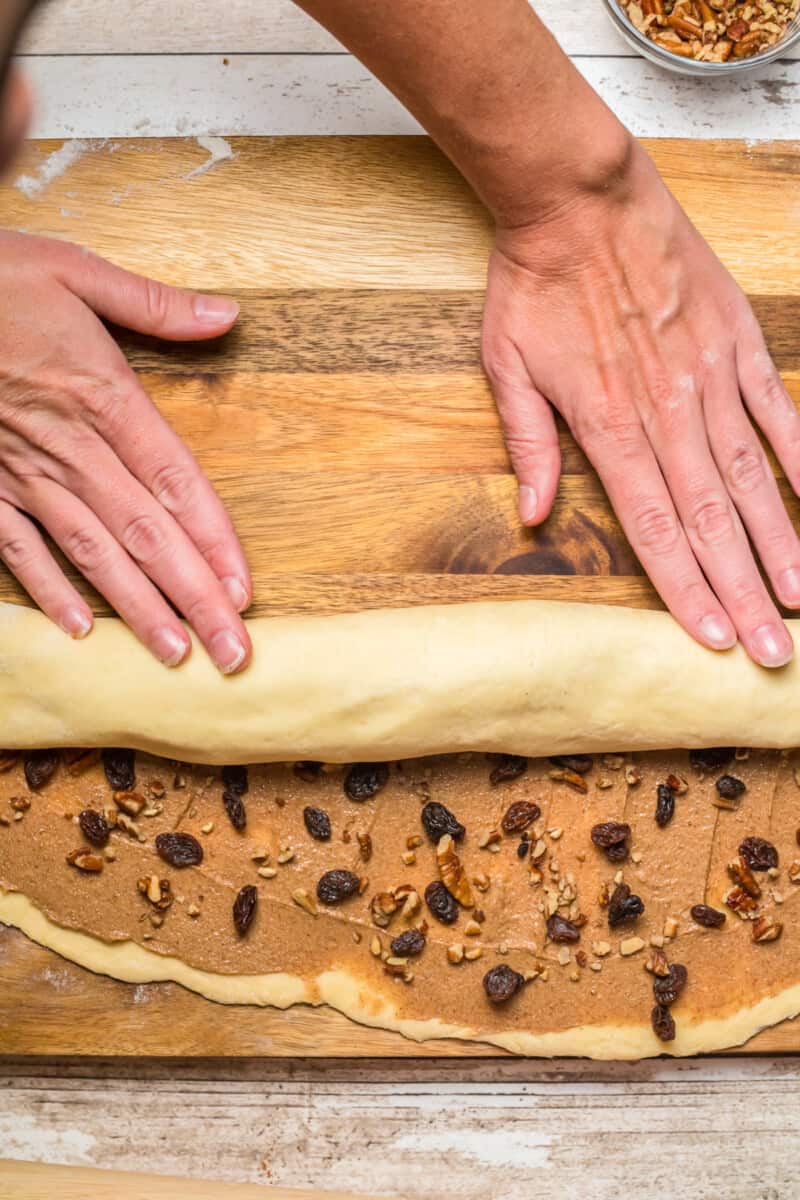 filled estonian kringle dough rolled up into a log on a wood cutting board.