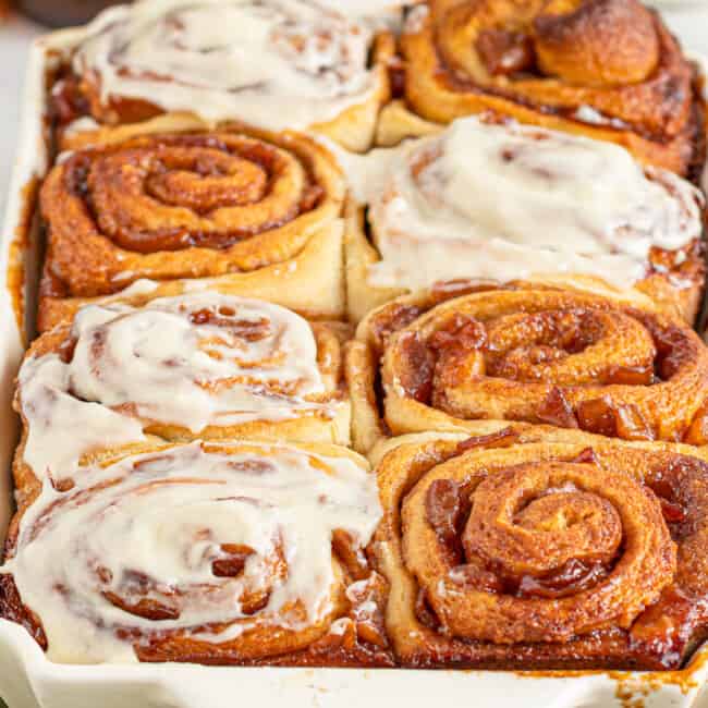 apple pie cinnamon rolls with frosting in pan