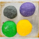 four different colored dough balls on a baking sheet.