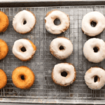 glazed donuts on a wire rack set in a baking sheet.