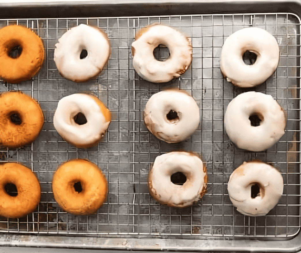 glazed donuts on a wire rack set in a baking sheet.