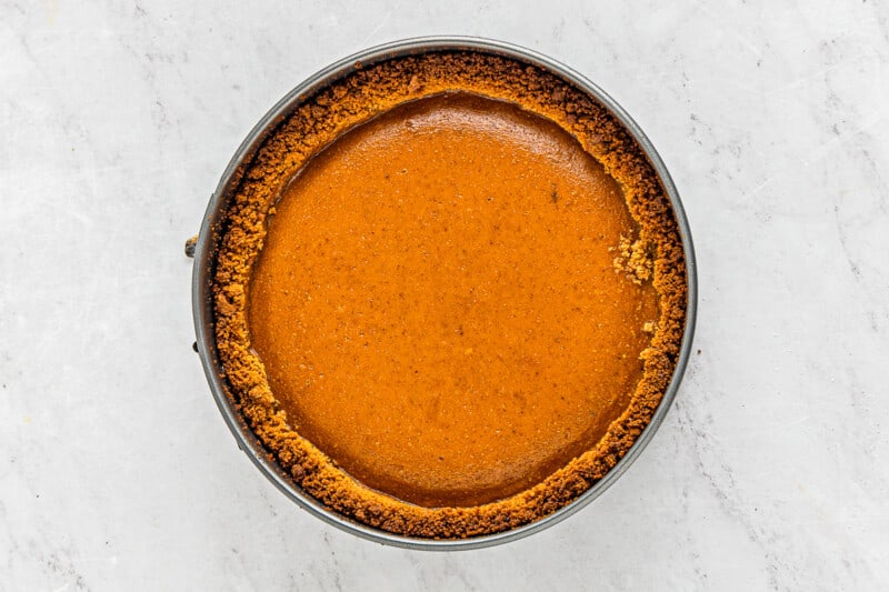 a pumpkin pie in a pan on a marble table.