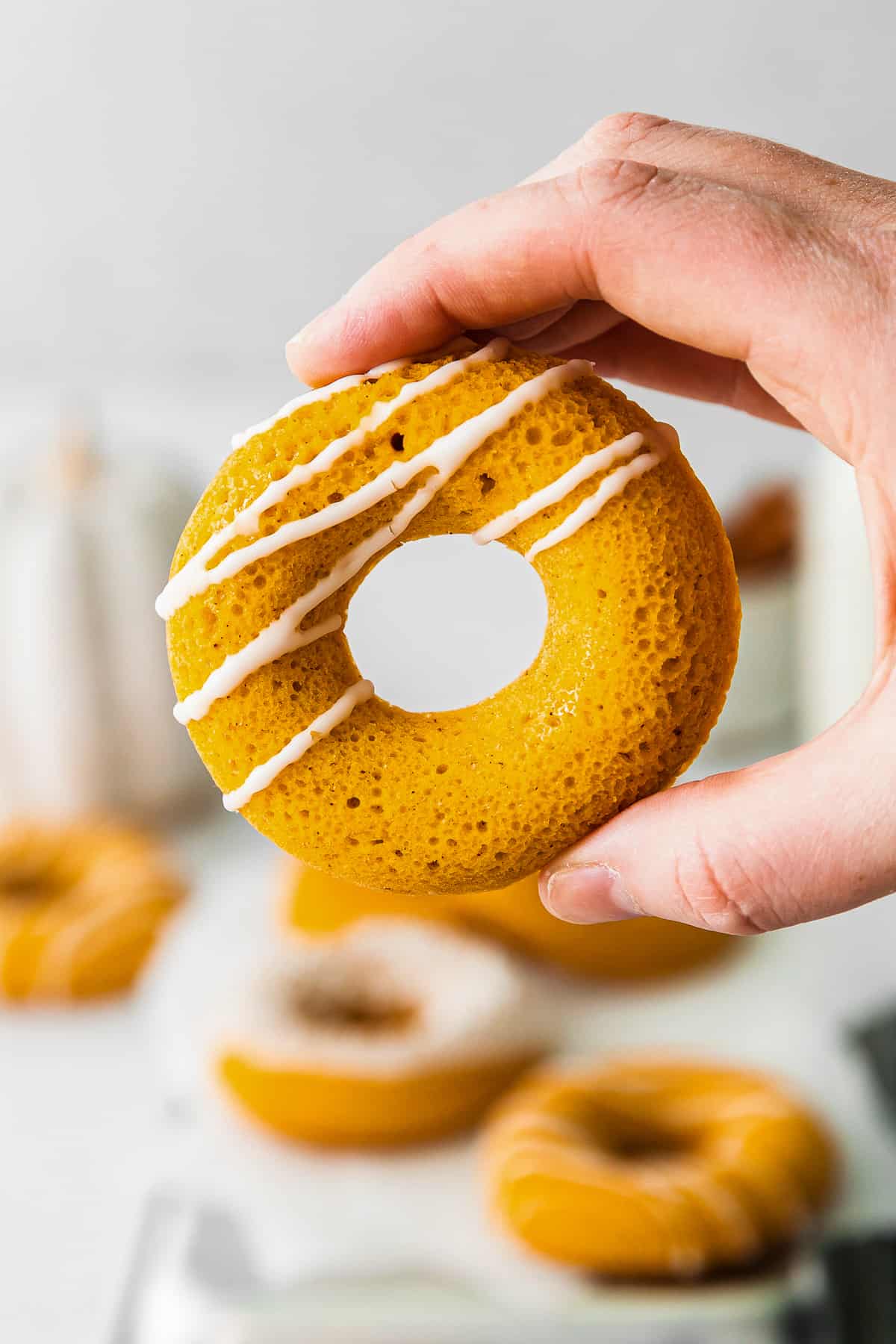 holding up pumpkin donut with drizzled icing