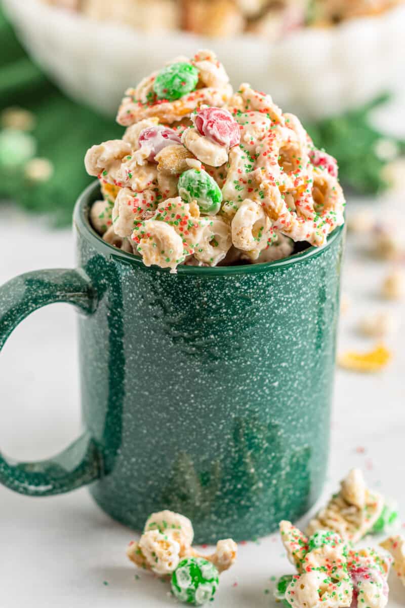 green mug filled with christmas chex mix