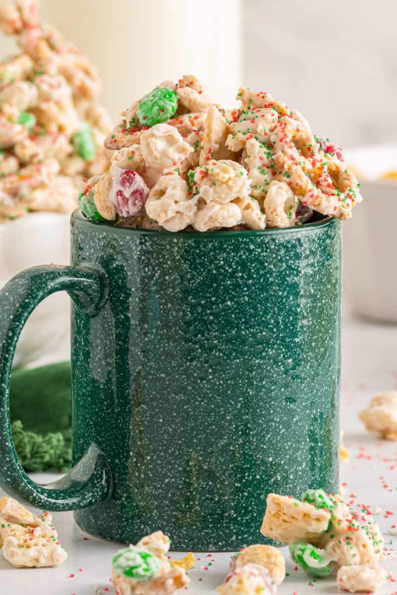 green mug filled with christmas chex mix