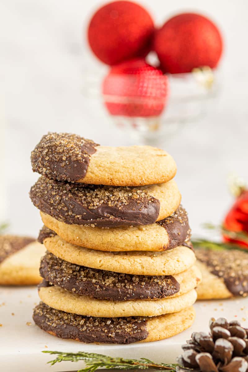 stack of sugar cookies with half of each cookie dipped in chocolate