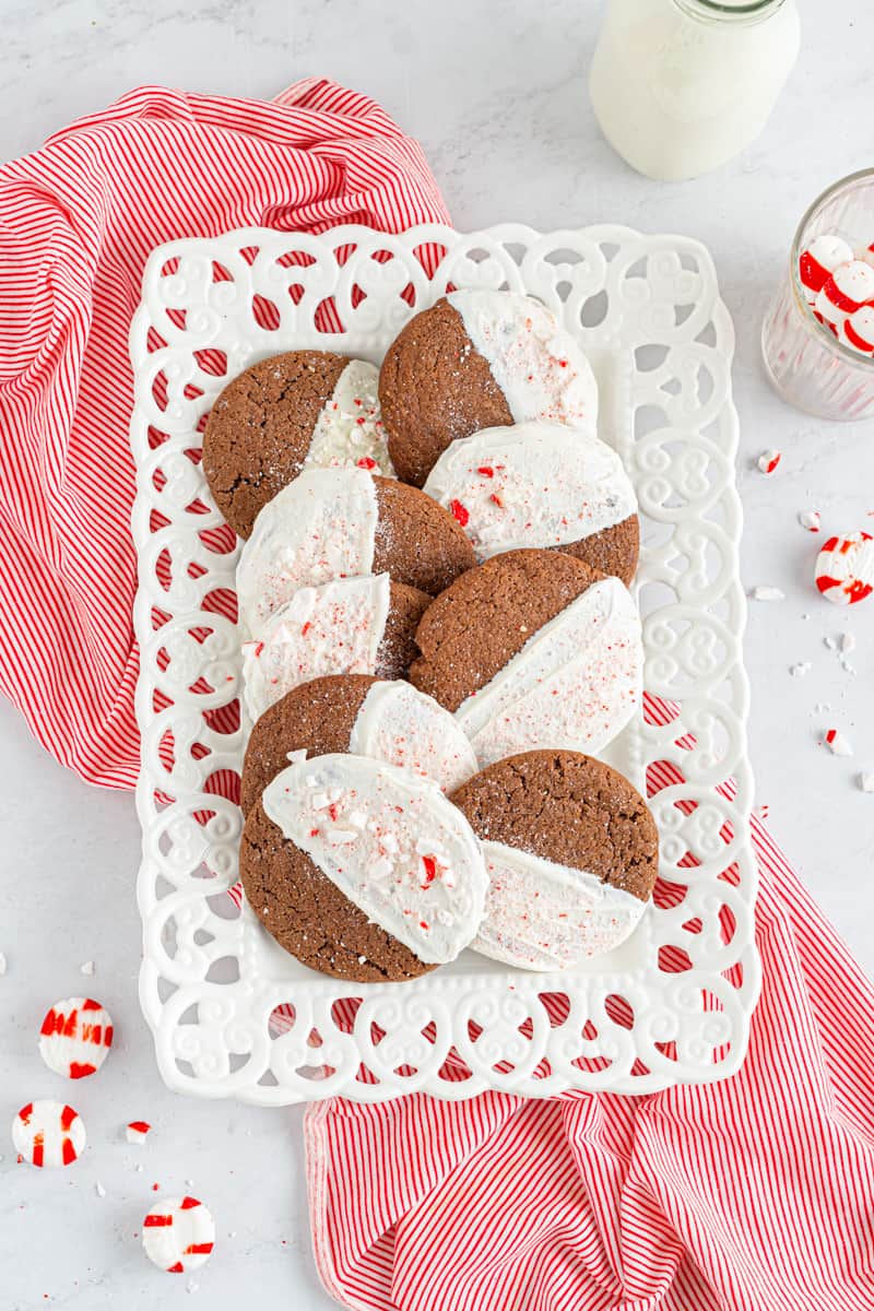overhead image of chocolate sugar cookies dipped in white chocolate and sprinkled with crushed peppermint on a white serving tray