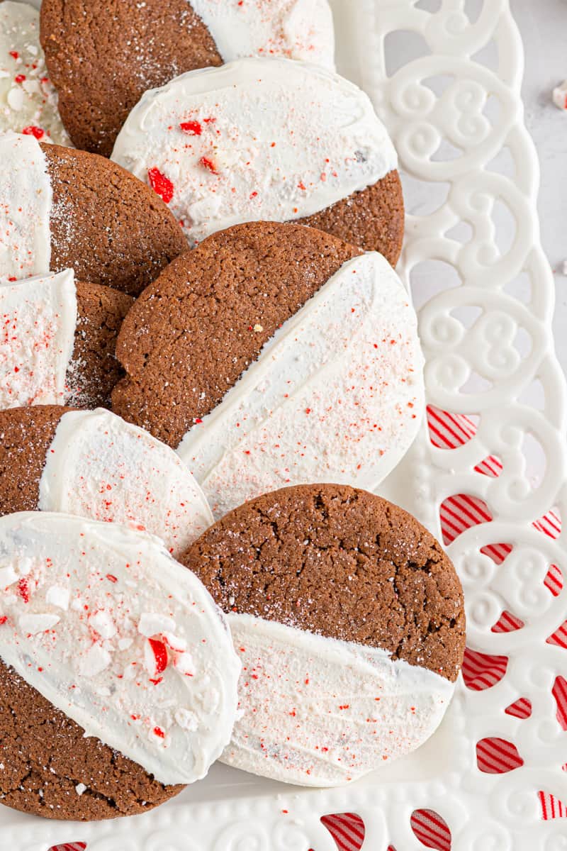 chocolate sugar cookies dipped in white chocolate and sprinkled with crushed peppermint on a white serving tray