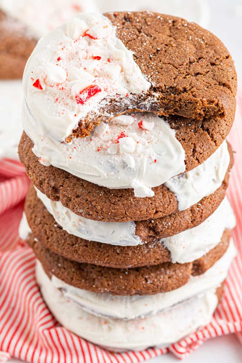 stack of chocolate sugar cookies dipped in white chocolate and sprinkled with crushed peppermint with a bite taken from one cookie