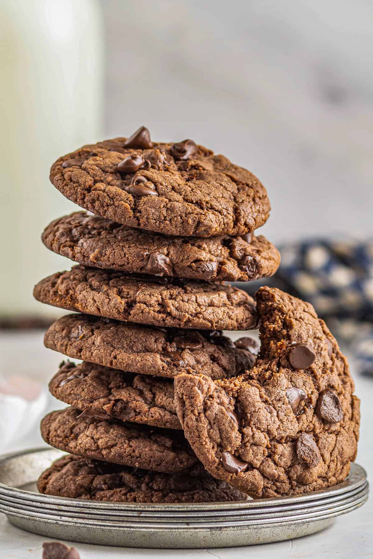 stack of chocolate cookies with chocolate chips with a cookie on the side with a bite taken